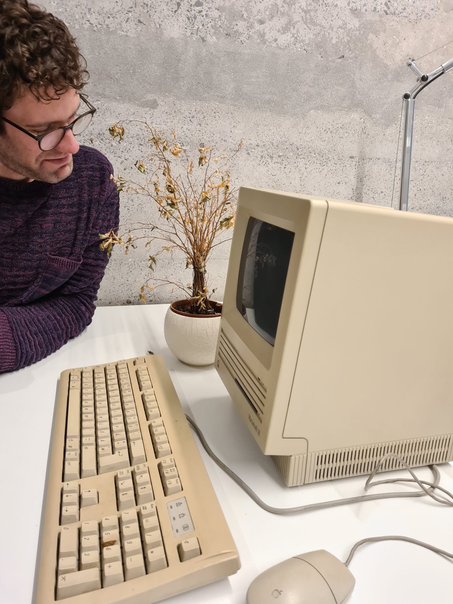 Bastian am alten Apple Rechner mit verwelkter Blume